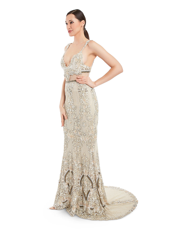 This ivory tone sequined dress features a plunging neckline, waist accentuating cut out, fitted silhouette and a floor sweeping trail. Hand embroidered gown that is decorated al over to keep you shinning.